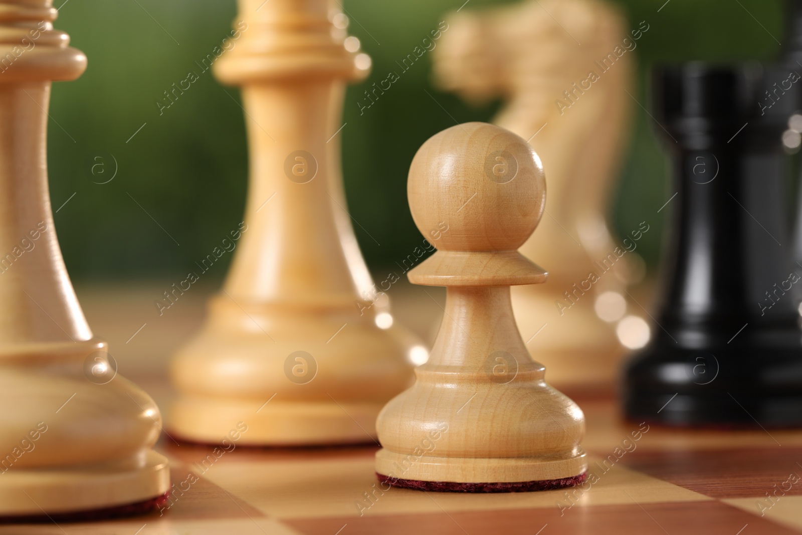 Photo of White pawn and other chess pieces on game board against blurred background, closeup