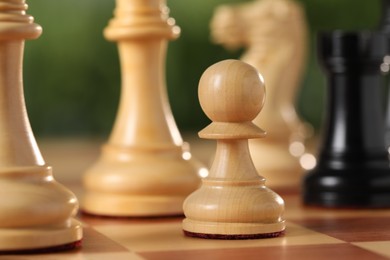 Photo of White pawn and other chess pieces on game board against blurred background, closeup