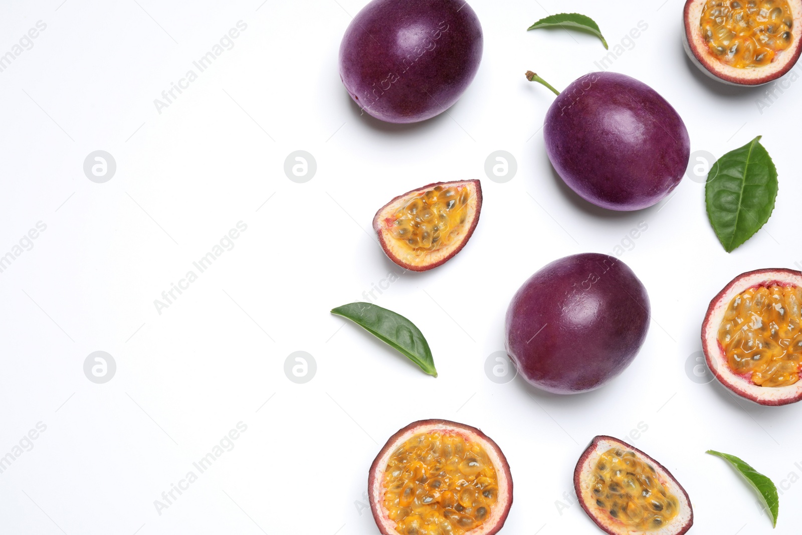 Photo of Fresh ripe passion fruits (maracuyas) with leaves on white background, flat lay. Space for text