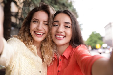 Beautiful young women taking selfie outdoors on sunny day