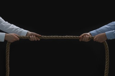 Photo of Dispute concept. Men pulling rope on black background, closeup