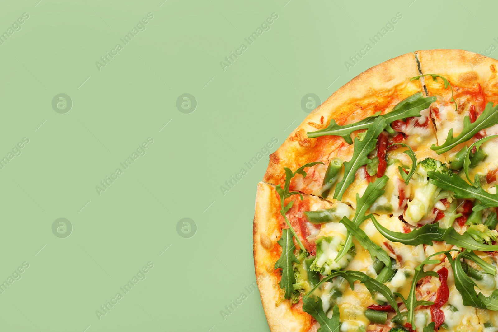 Photo of Delicious vegetarian pizza on green table, top view. Space for text