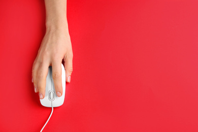 Photo of Woman using modern wired optical mouse on red background, top view. Space for text