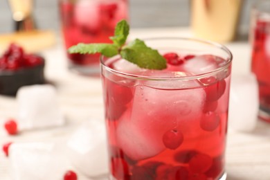 Photo of Tasty cranberry cocktail with ice cubes in glass on table, closeup