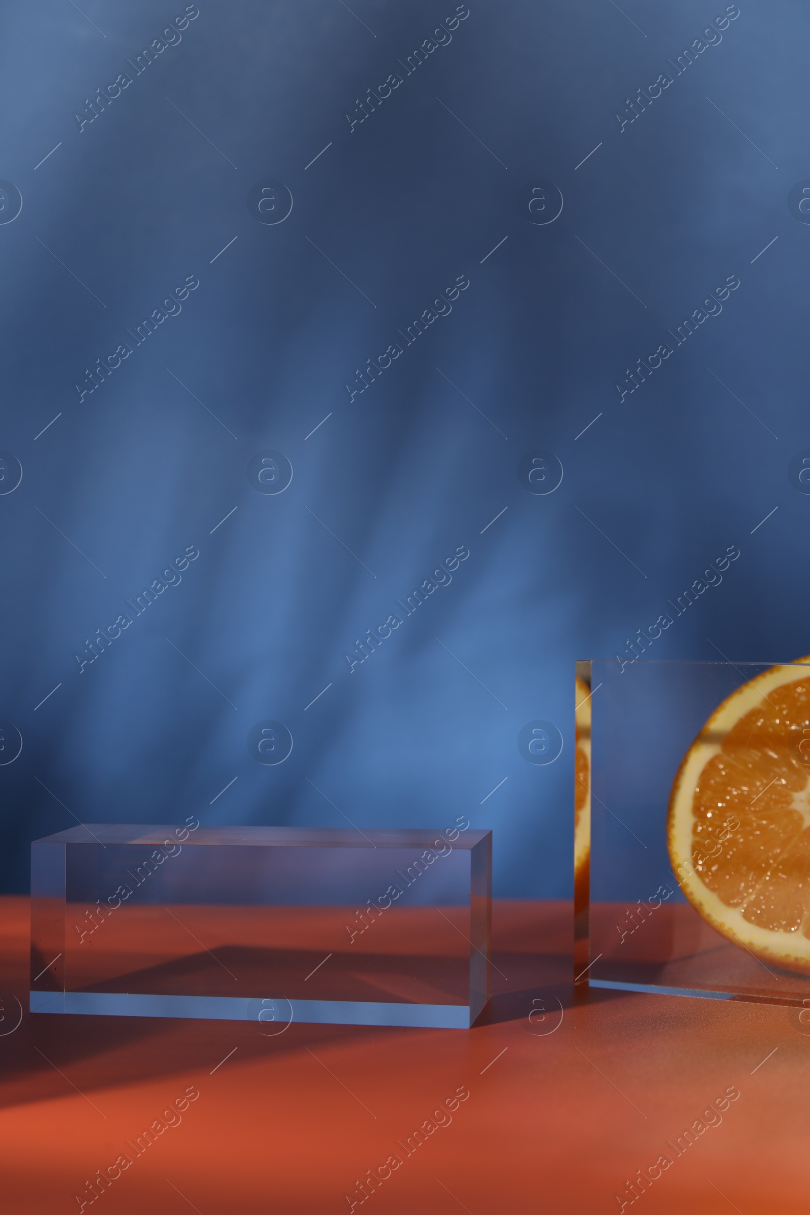 Photo of Presentation for product. Podium and tasty fresh oranges on red table against blue background, closeup. Space for text