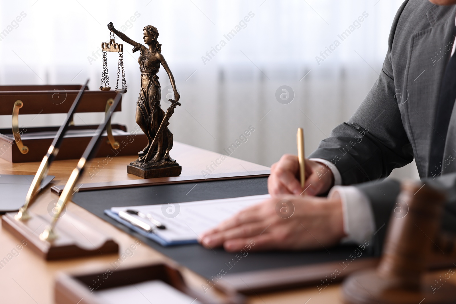 Photo of Notary writing notes at wooden table in office, closeup