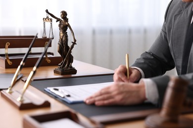 Notary writing notes at wooden table in office, closeup