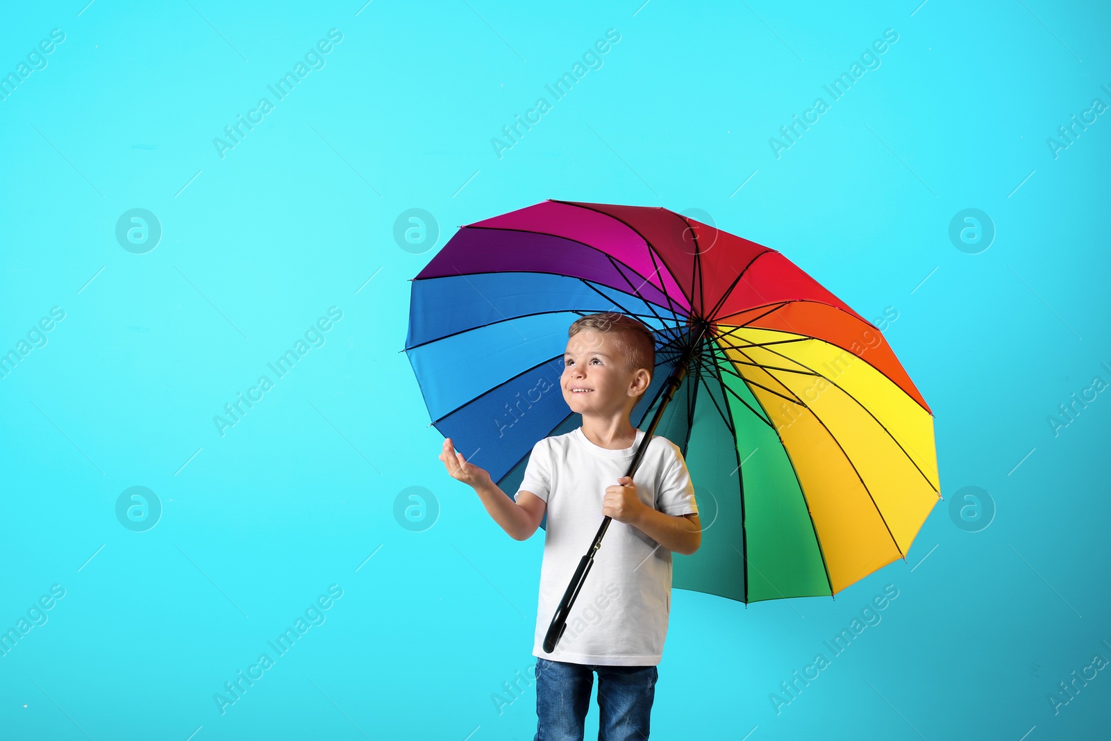 Photo of Little boy with rainbow umbrella on color background