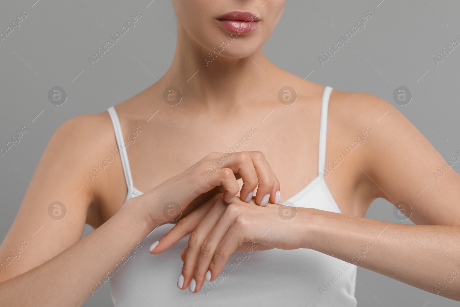 Photo of Woman with dry skin checking her arm on gray background, closeup