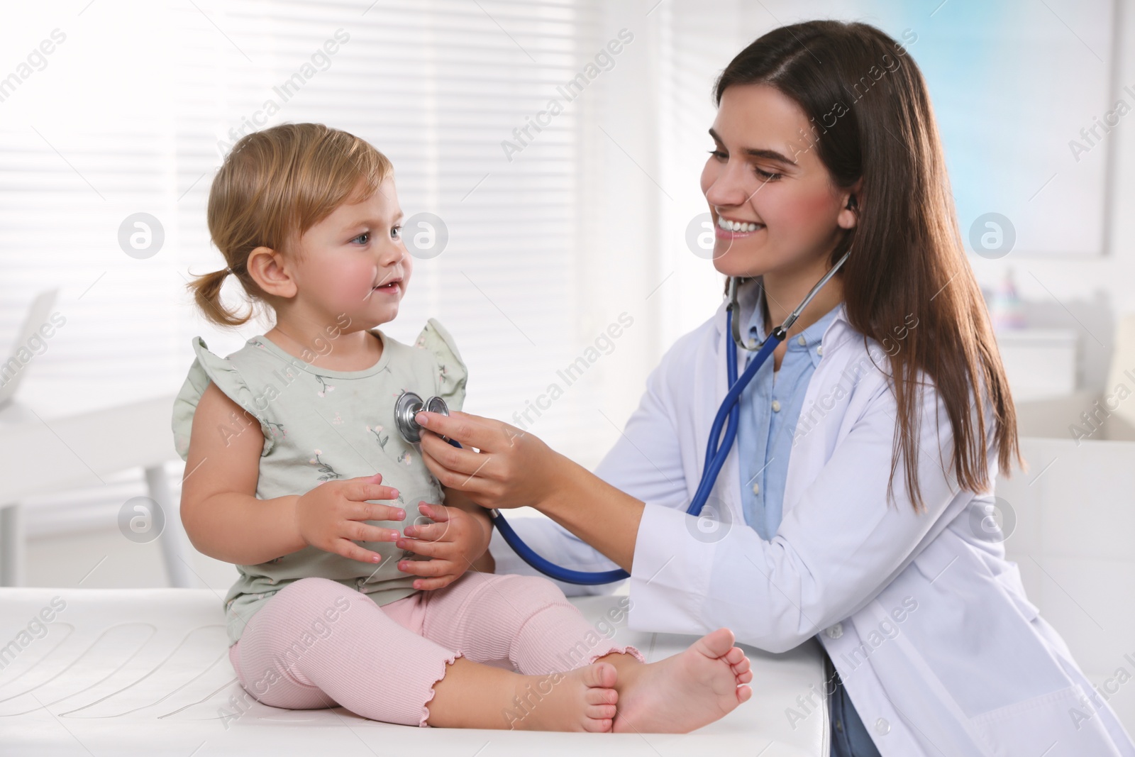 Photo of Pediatrician examining baby with stethoscope in clinic