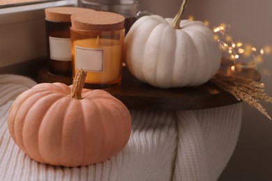 Beautiful pumpkins and scented candles on window sill indoors