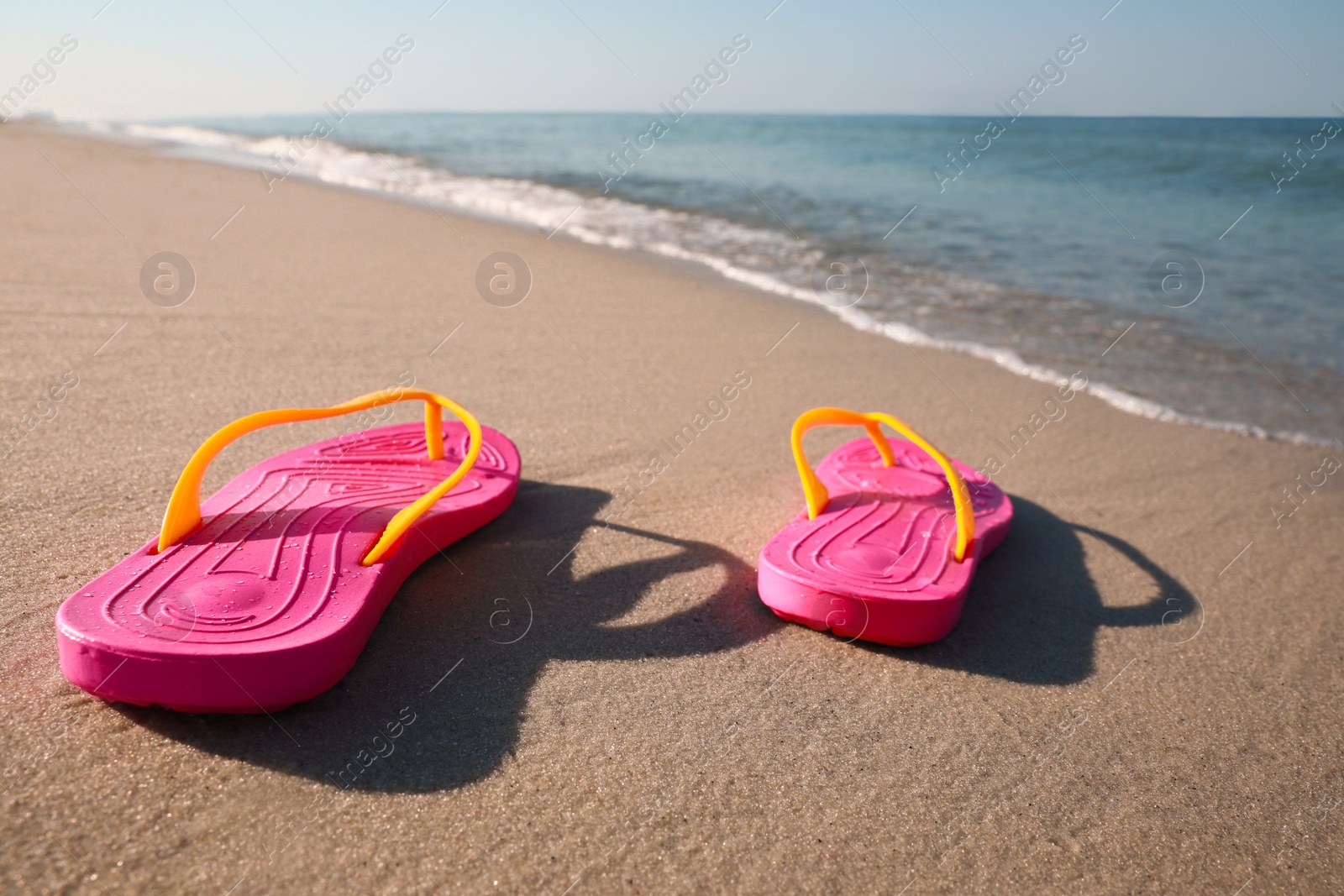 Photo of Pair of stylish flip flops on beach