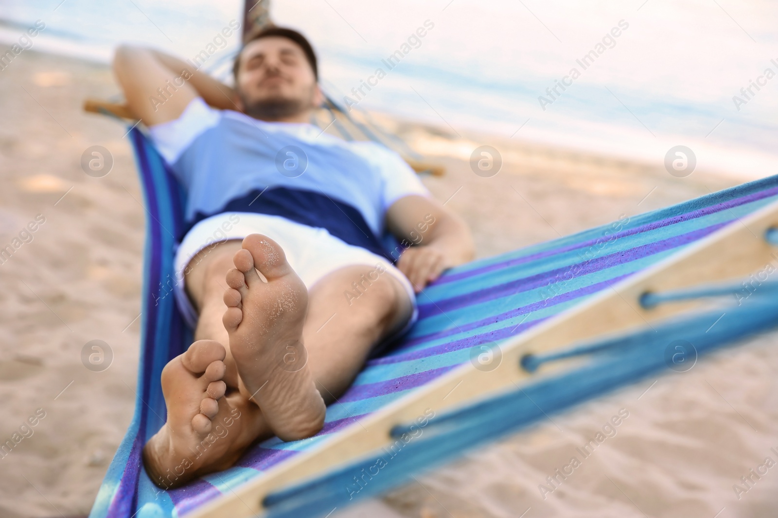 Photo of Young man lying in hammock at seaside. Summer vacation