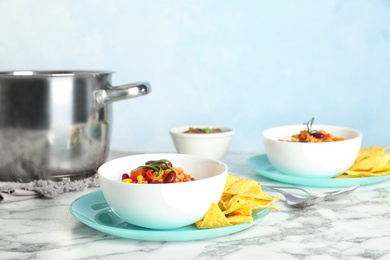 Photo of Bowl with tasty chili con carne served on marble table