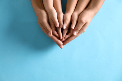 Mother holding hands with her children on blue background, top view. Happy family