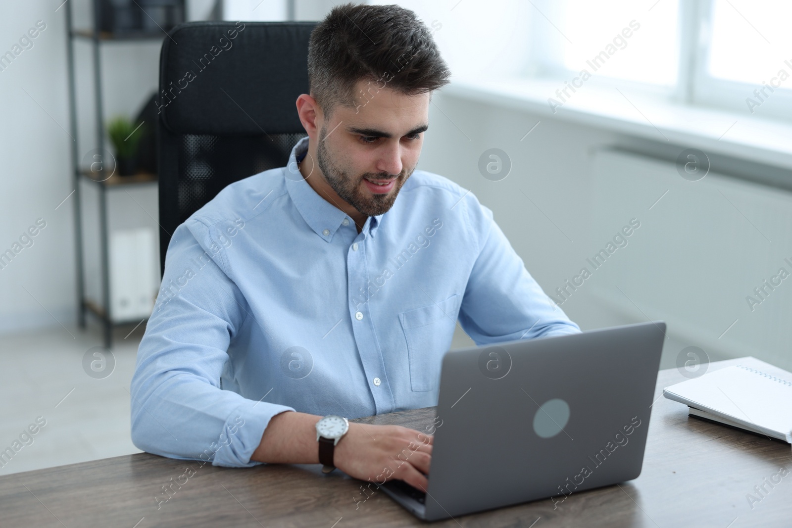 Photo of Young programmer working with laptop in office