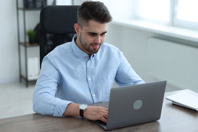 Young programmer working with laptop in office