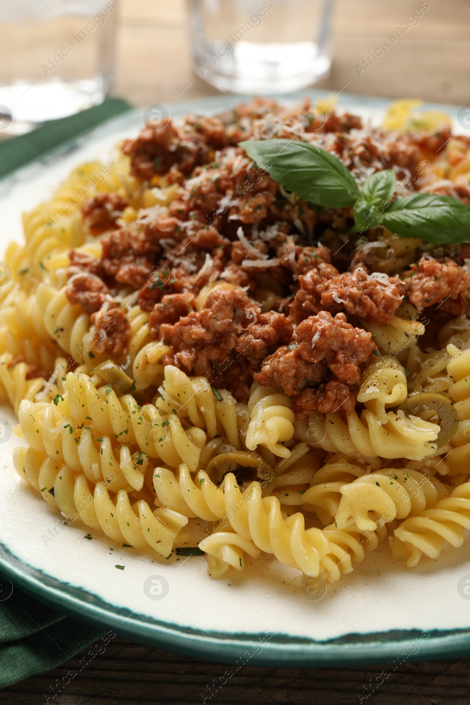 Photo of Plate of delicious pasta with minced meat and basil on table, closeup