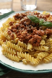 Plate of delicious pasta with minced meat and basil on table, closeup