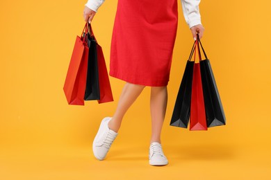 Photo of Woman with shopping bags on yellow background, closeup