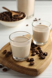 Photo of Coffee cream liqueur in glasses and beans on white wooden table
