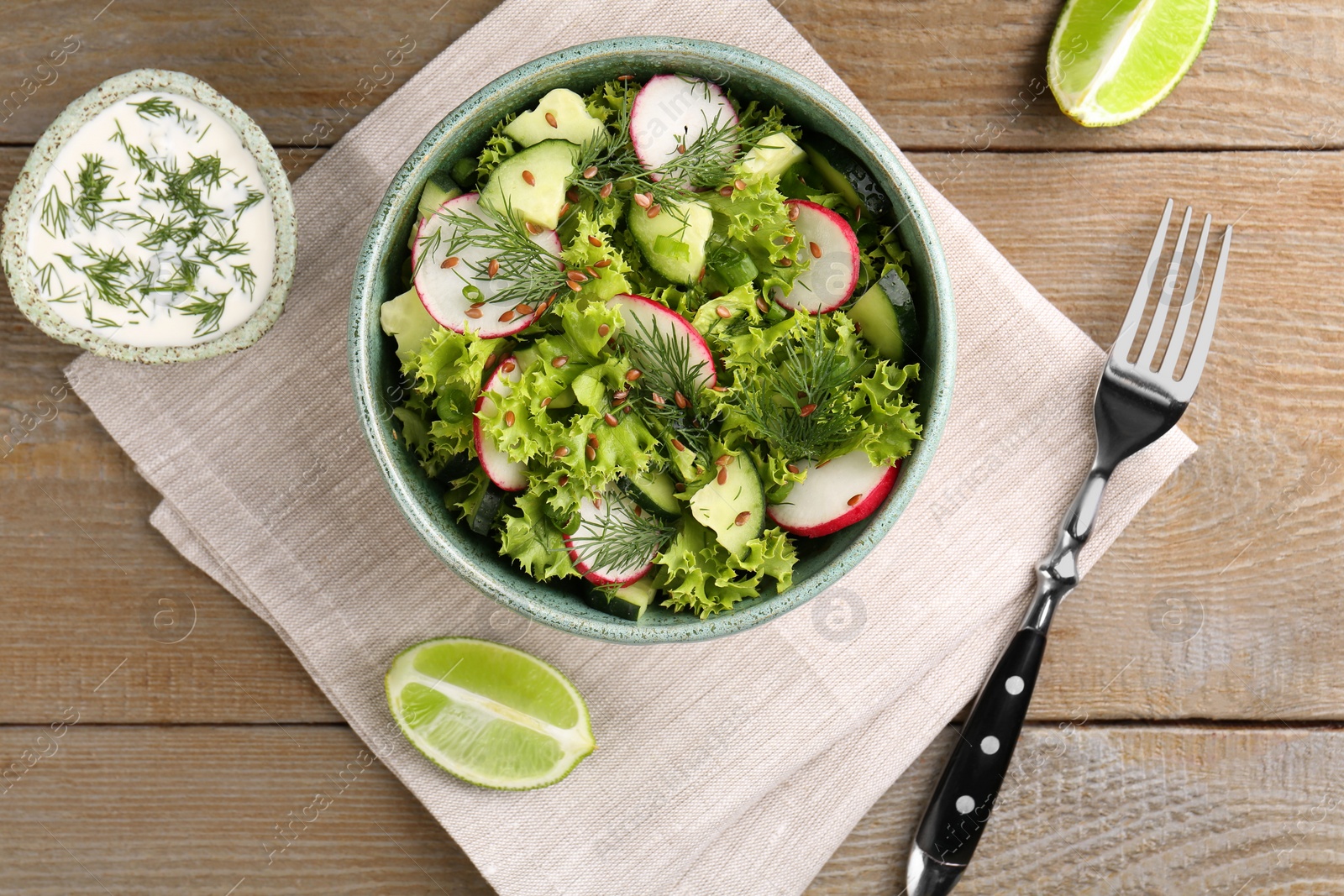 Photo of Delicious salad with radish, cucumber and lettuce served on wooden table, flat lay