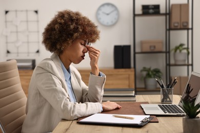 Woman suffering from headache at workplace in office