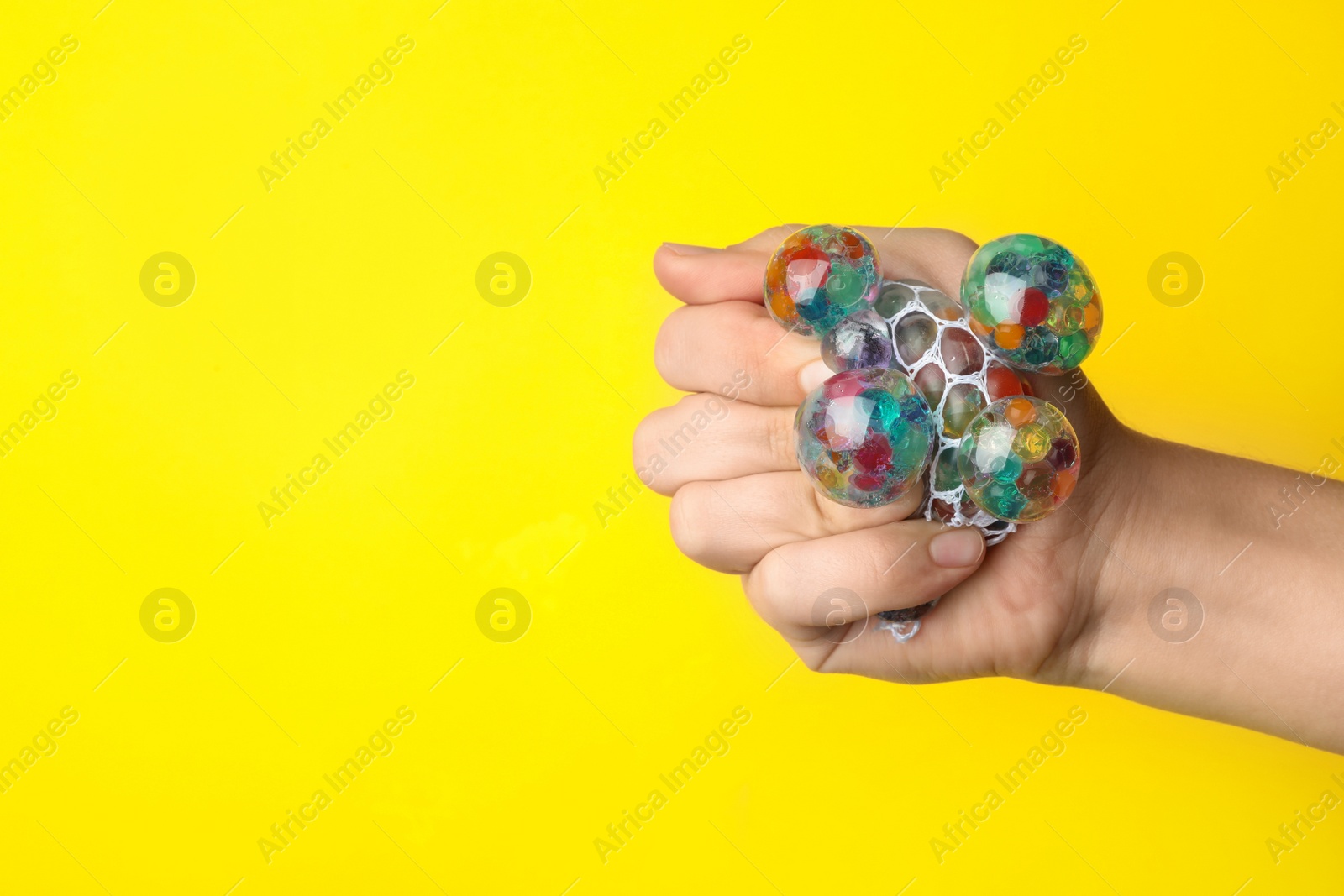 Photo of Woman squeezing colorful slime on yellow background, closeup. Antistress toy