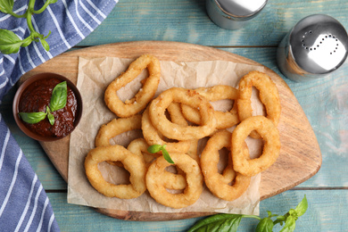 Photo of Fried onion rings served on blue wooden table, flat lay