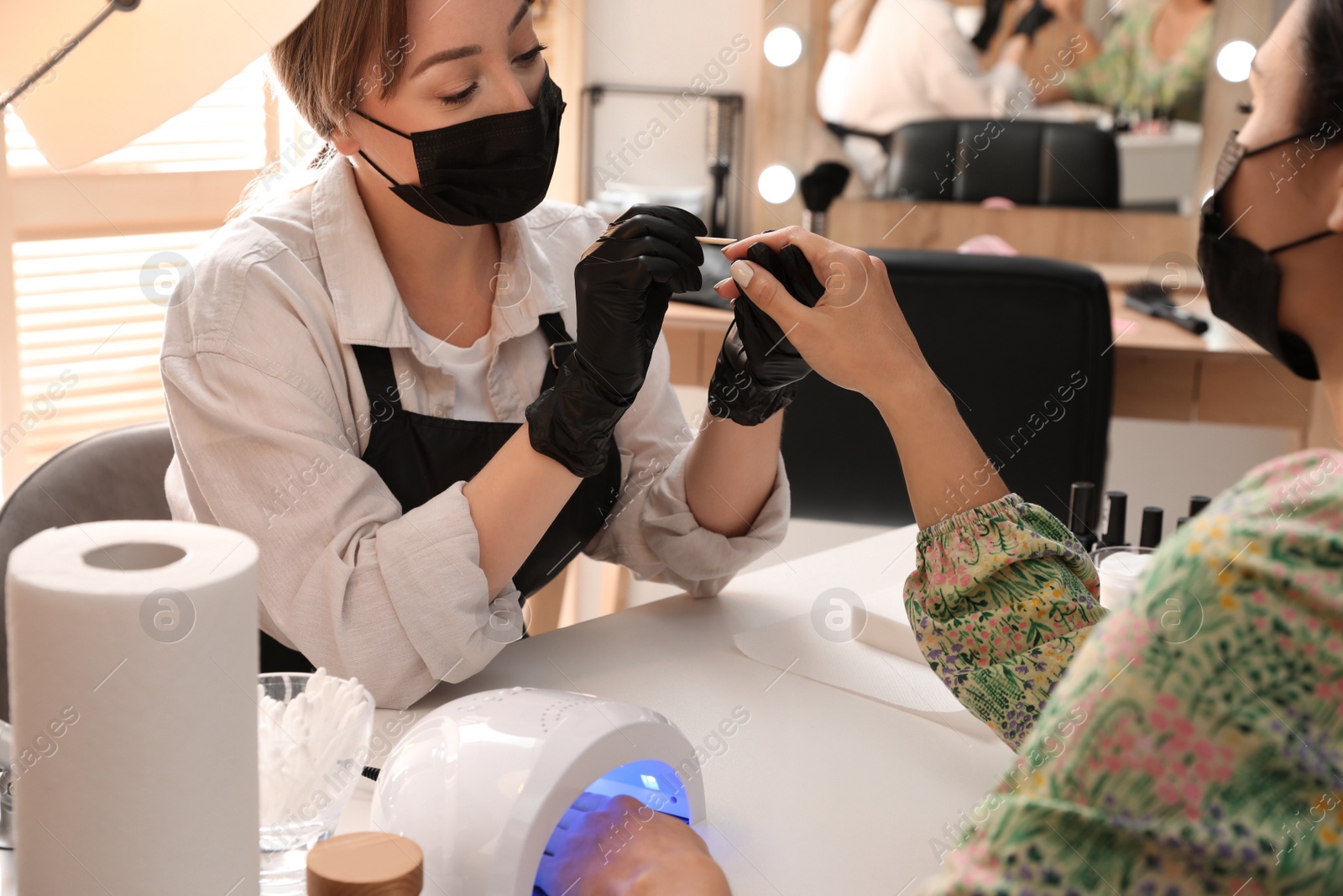 Photo of Professional manicurist working with client in salon. Beauty services during Coronavirus quarantine