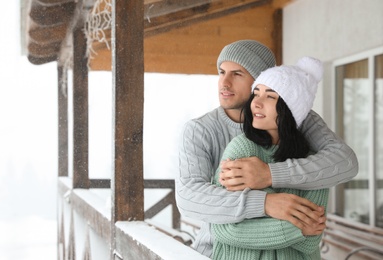 Photo of Lovely couple wearing warm sweaters and hats outdoors on snowy day. Winter season