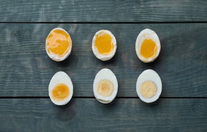 Different readiness stages of boiled chicken eggs on blue wooden table, flat lay