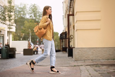 Photo of Young woman with backpack walking on city street