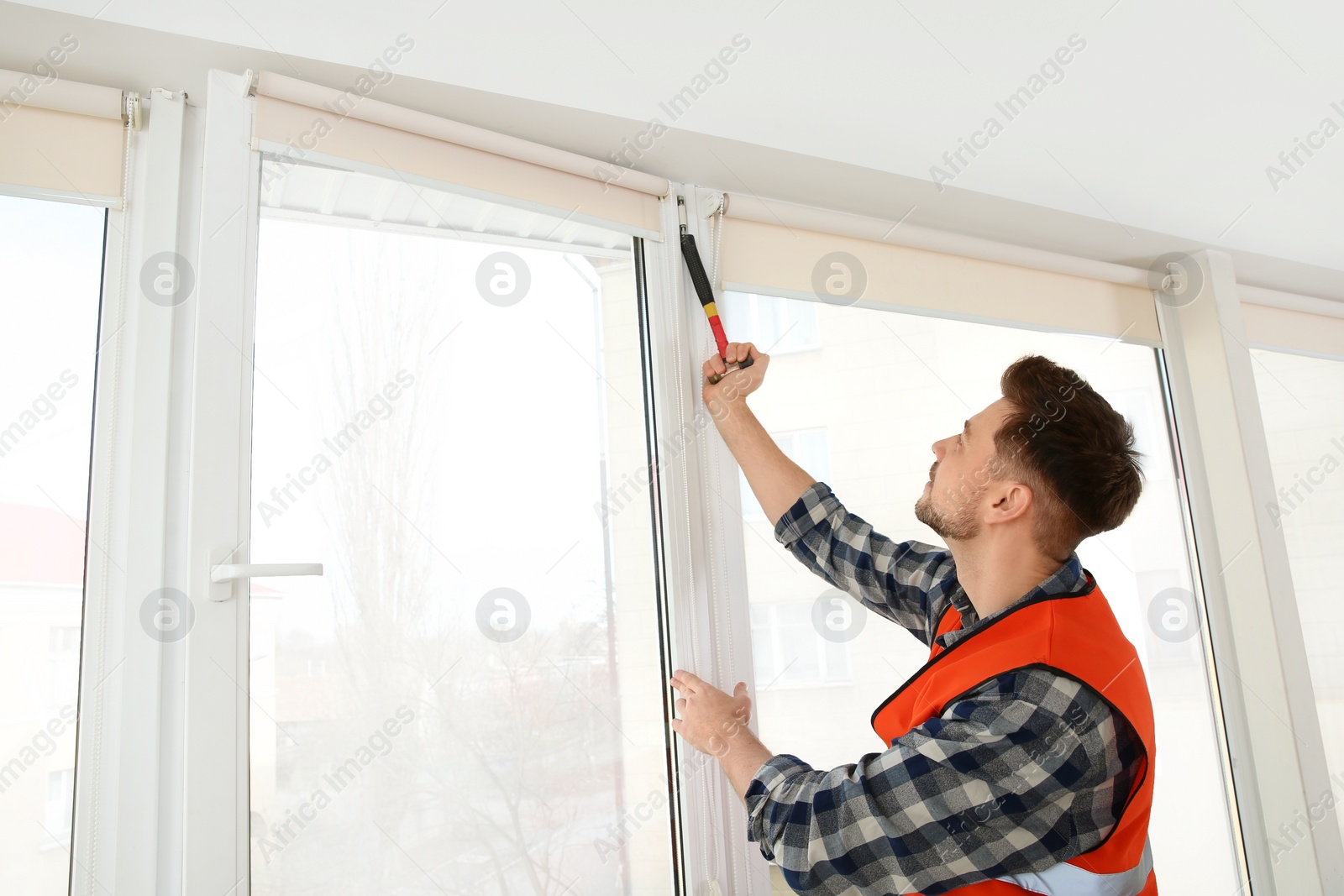 Photo of Construction worker installing plastic window in house