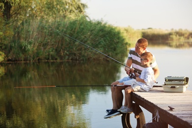 Photo of Dad and son fishing together on sunny day