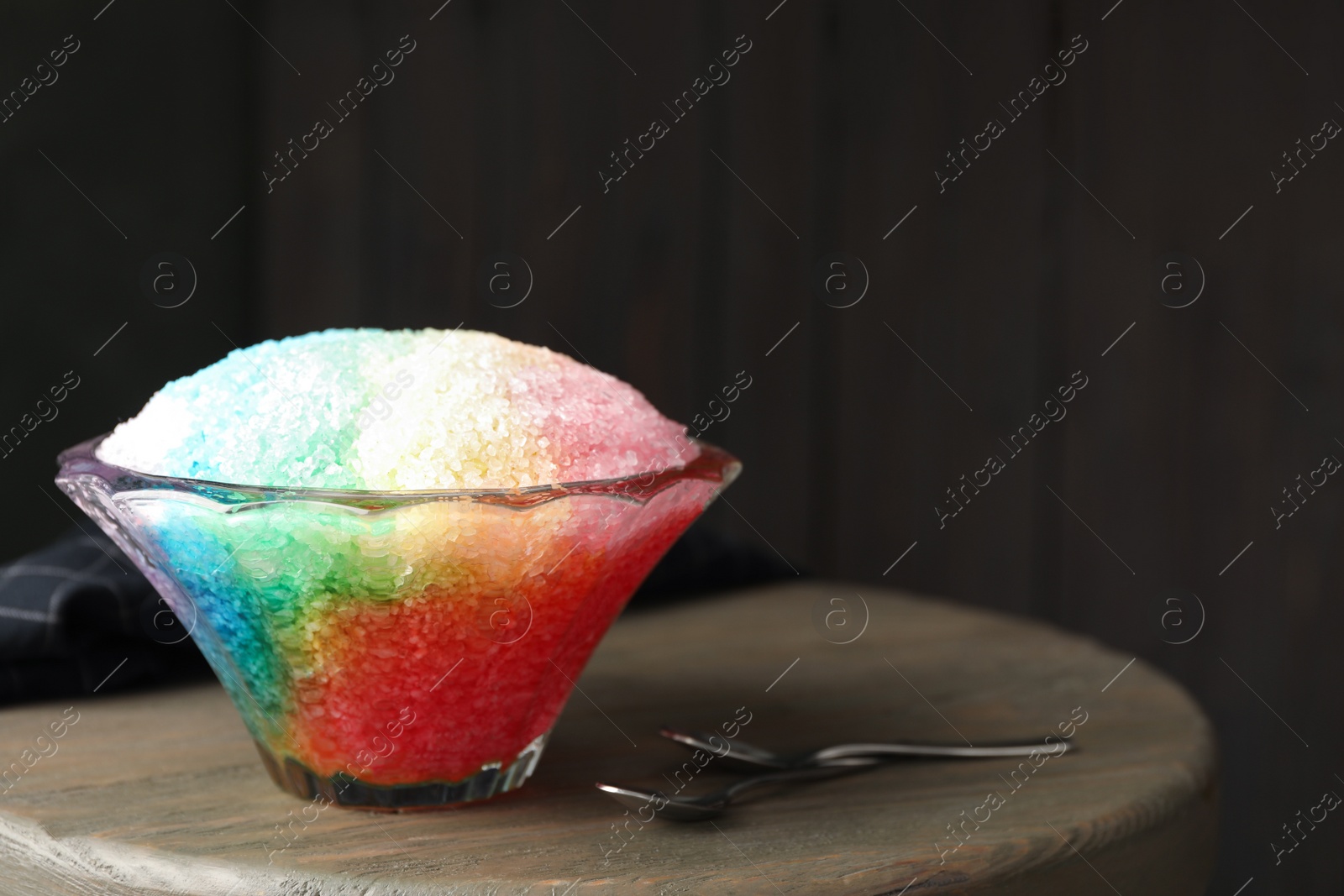 Photo of Rainbow shaving ice in glass dessert bowl on wooden table indoors