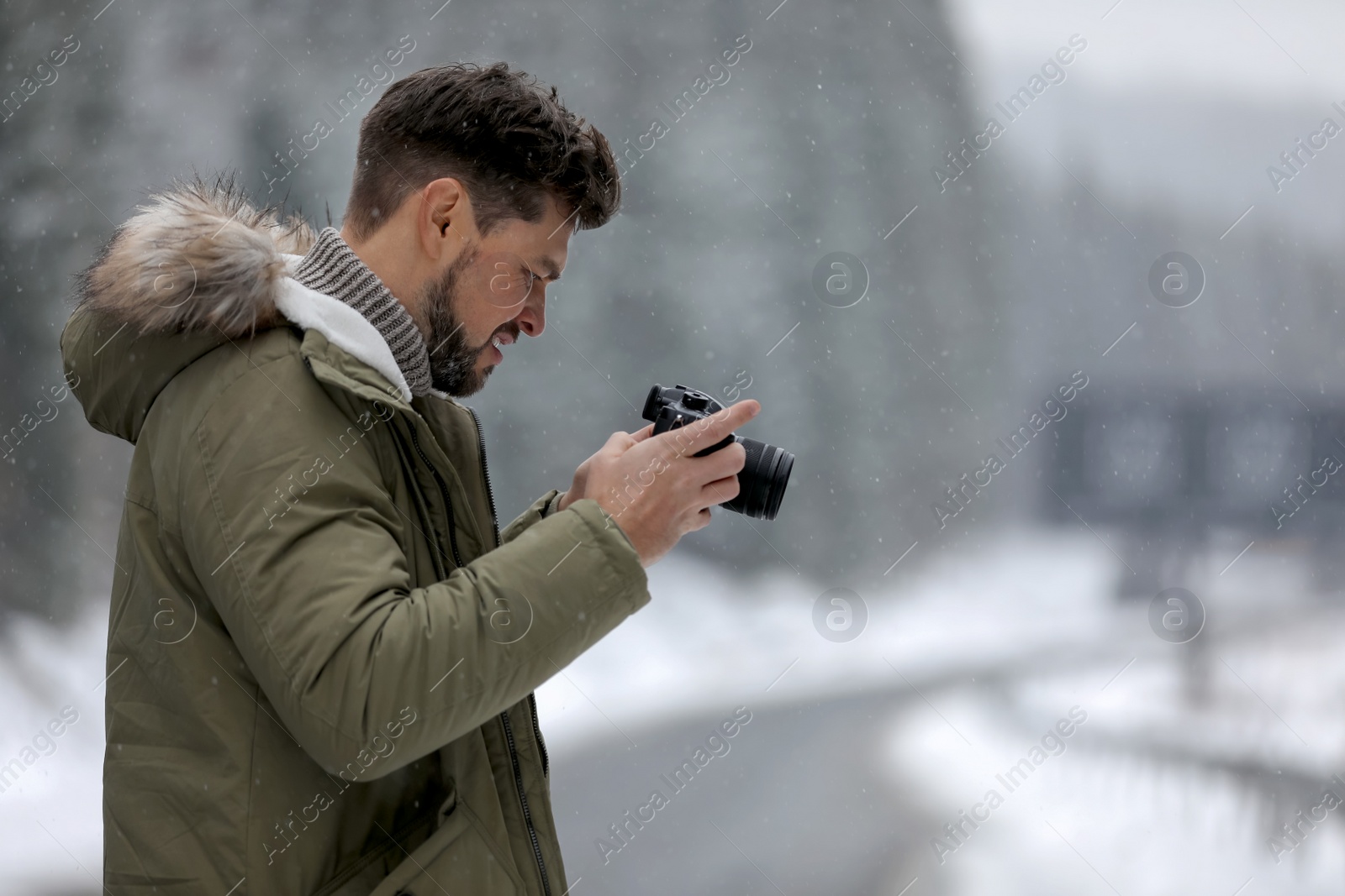 Photo of Male photographer with camera on snowy road, space for text. Winter vacation