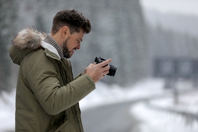 Male photographer with camera on snowy road, space for text. Winter vacation