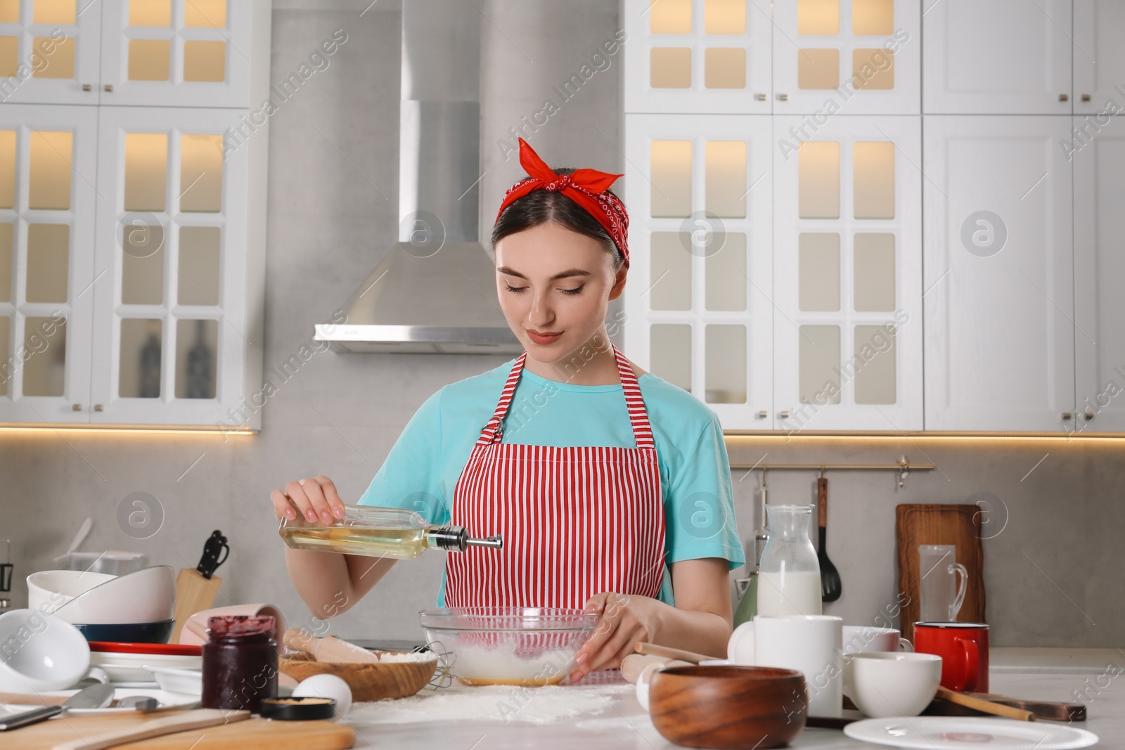 Photo of Beautiful woman cooking in kitchen. Dirty dishware, food leftovers and utensils on messy countertop