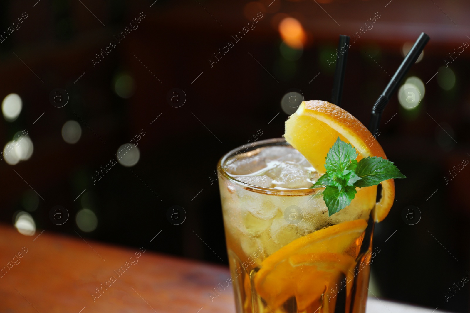 Photo of Glass of delicious cocktail with ice on blurred background, closeup