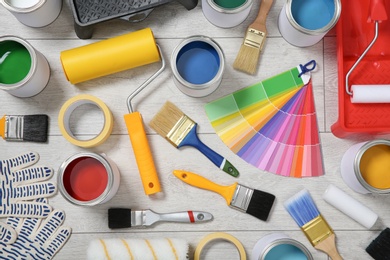 Photo of Flat lay composition with cans of paint and decorator tools on wooden background