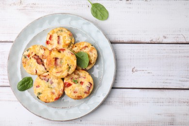 Delicious egg muffins with cheese and bacon on white wooden table, top view. Space for text