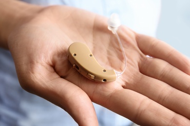 Photo of Woman holding hearing aid, closeup of hand