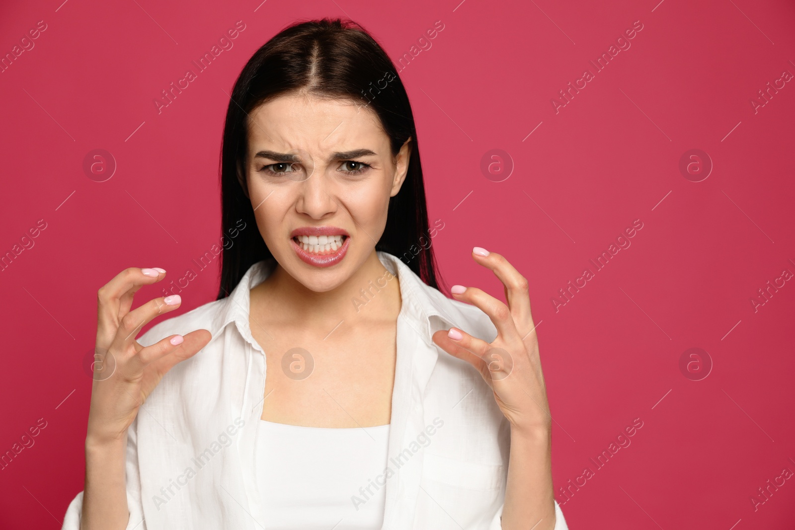 Photo of Angry young woman on pink background. Hate concept