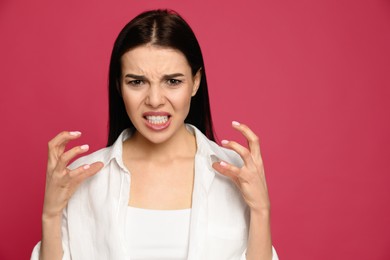 Photo of Angry young woman on pink background. Hate concept