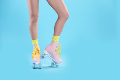 Photo of Young woman with retro roller skates on color background, closeup. Space for text
