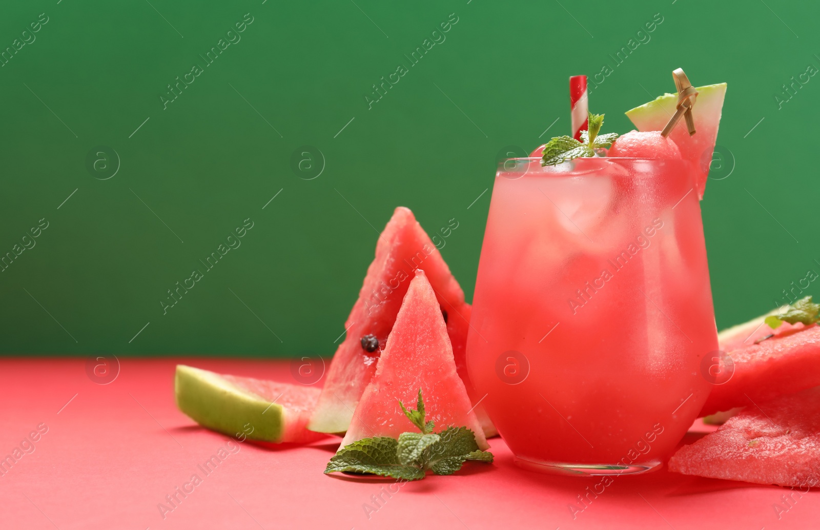 Photo of Tasty watermelon drink and fresh fruits on red table against green background. Space for text
