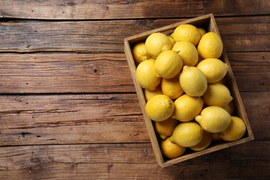 Fresh lemons in crate on wooden table, top view. Space for text