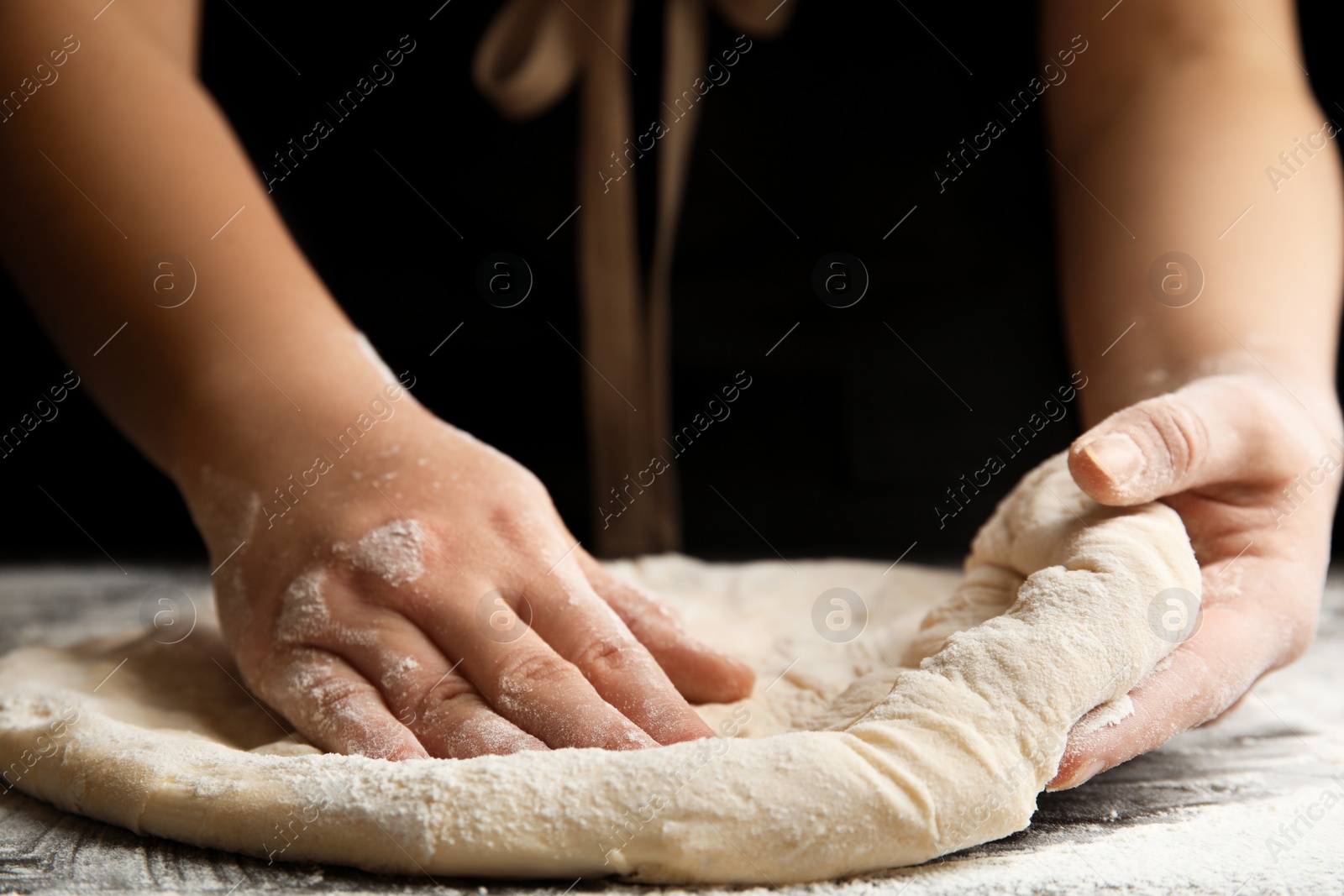 Photo of Woman kneading dough for pizza at grey table, closeup