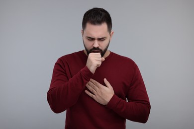 Photo of Sick man coughing on gray background. Cold symptoms